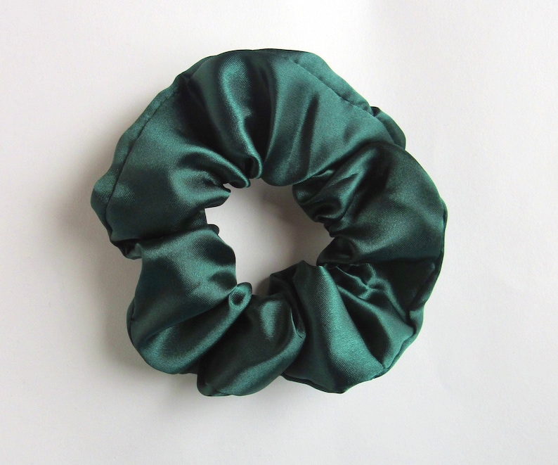 Pu&ograve; includere: Un elastico per capelli in raso verde scuro.