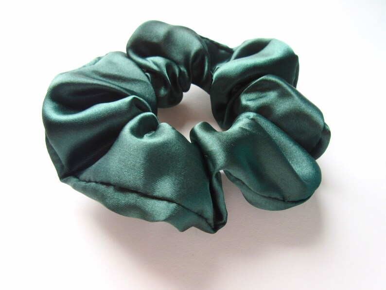 Pu&ograve; includere: Un elastico per capelli in raso verde scuro.