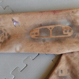 Puede incluir: Una chaqueta de ante marr&oacute;n con un aspecto desgastado. La chaqueta tiene un dise&ntilde;o de plantilla en la manga, con un patr&oacute;n circular y una forma rectangular con agujeros.