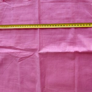 May include: A pink fabric garment with a seam down the center. A yellow measuring tape is placed across the fabric, showing a measurement of 40 inches.