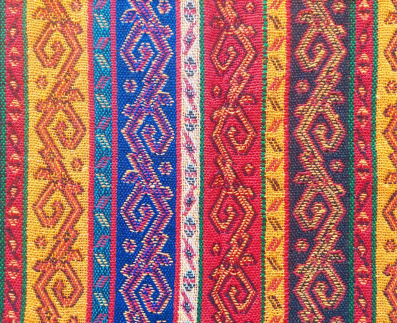 May include: Close-up of a woven textile with vertical stripes in various colors. The stripes include patterns in orange, blue, red, and yellow. The design features geometric and stylized floral motifs.