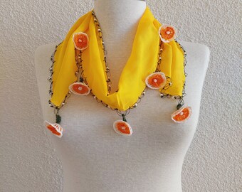 May include: A yellow crocheted scarf with orange flower accents. The scarf is displayed on a white mannequin.