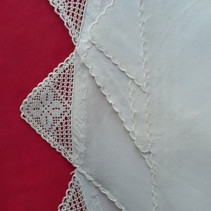 May include: Three white cotton handkerchiefs with crocheted lace edging. The handkerchiefs are layered on top of each other, with the lace edging visible on all three.