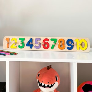 May include: Wooden number puzzle with colorful numbers 1 through 10. The numbers are on a wooden board and can be removed and replaced. This is a great educational toy for children.