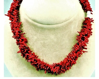 Puede incluir: Un collar de coral rojo hecho de pequeñas piezas finas de coral. El collar se muestra en un busto de maniquí blanco.