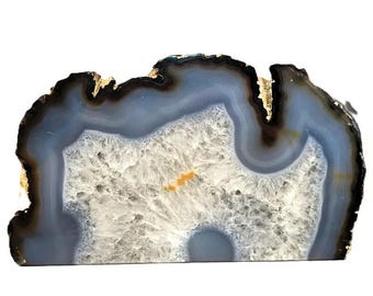 May include: A large, natural agate slice with a blue and white banded pattern. The agate has a rough, natural edge and a smooth, polished surface. The agate is a beautiful example of the natural beauty of crystals.