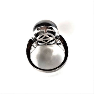 May include: A silver ring with a black gemstone set in a decorative silver setting. The ring is viewed from above.