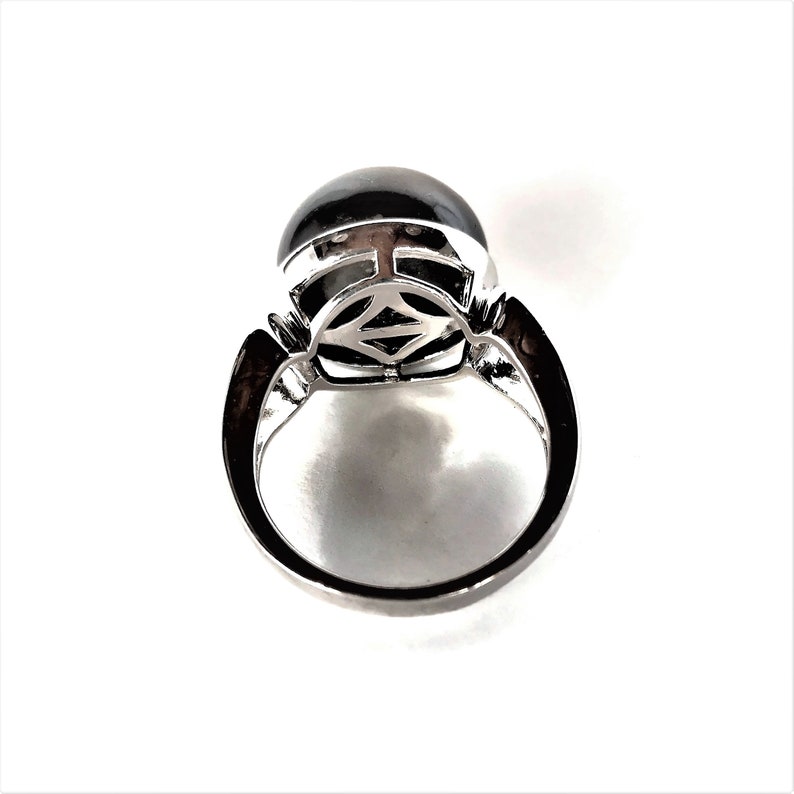 May include: A silver ring with a black gemstone set in a decorative silver setting. The ring is viewed from above.
