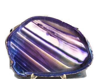 May include: A large, purple agate slice with a natural, striated pattern. The agate is displayed on a metal stand.