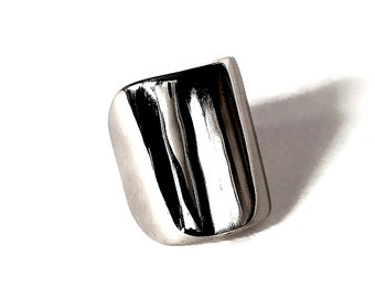 Puede incluir: Un anillo de plata con un diseño liso y curvo. El anillo está hecho de metal y tiene un acabado brillante.