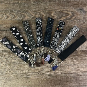Llavero de pulsera negro y blanco con borlas, diseño de pinza de langosta, de algodón gótico, resistente, con diseño de hueso de perro, pata de perro, flores, enredadera y galaxia negra.