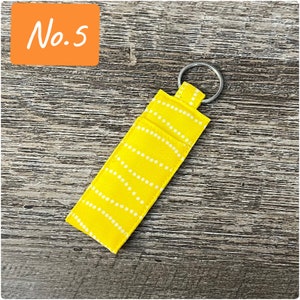May include: A yellow fabric keychain with a white dotted pattern and a silver key ring.