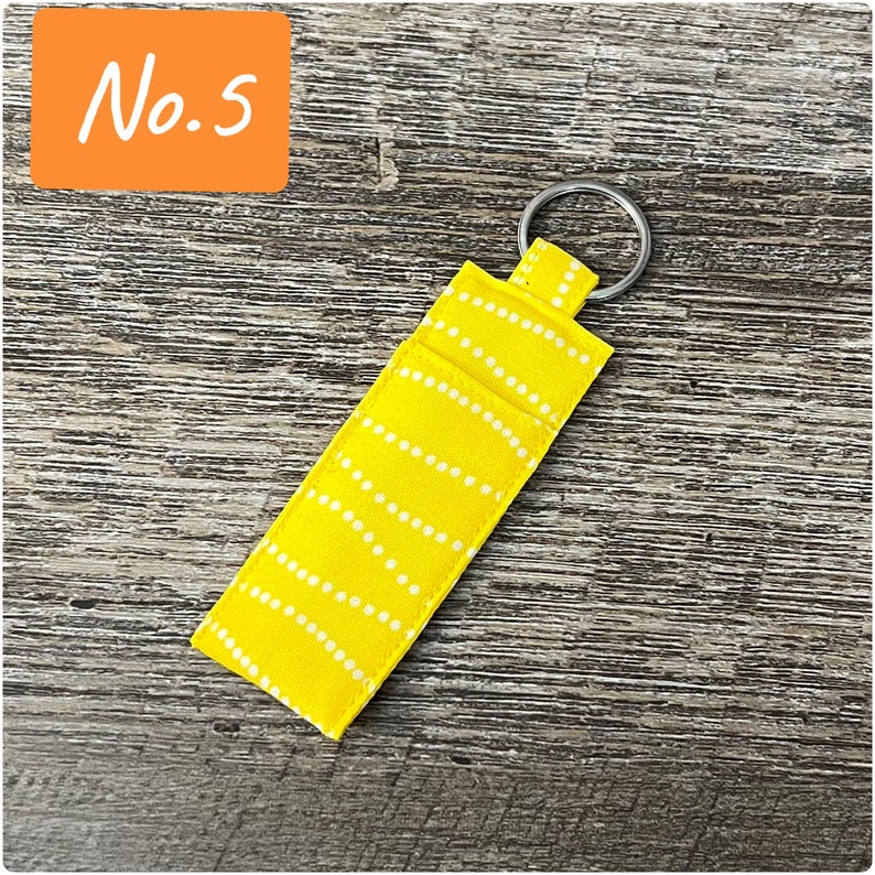 May include: A yellow fabric keychain with a white dotted pattern and a silver key ring.