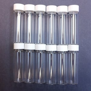 May include: A set of 12 clear glass vials with white screw-on caps. The vials are all the same size and shape, and they are arranged in a row.