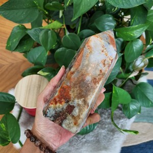 May include: A polished crystal tower featuring a blend of earthy tones including cream, translucent white, and deep rust-colored inclusions. The stone has a smooth, multi-faceted surface with visible natural mineral patterns throughout its structure.