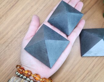 May include: Three black pyramid-shaped crystals of varying sizes. The crystals are smooth and have a matte finish.