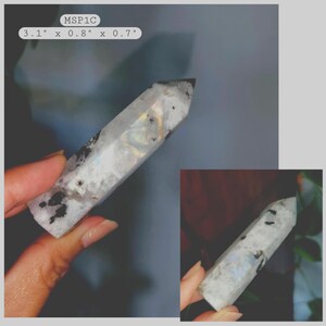 May include: A polished, hexagonal crystal tower with a translucent white base, iridescent flashes of blue and gold, and scattered black mineral inclusions. The item is labeled MSP1C and measures 3.1 inches by 0.8 inches by 0.7 inches.