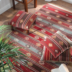 May include: A red, brown, and grey striped rug with matching cushions and a footstool. The rug and footstool have a geometric pattern. The cushions are rectangular. The rug measures approximately 152 cm by 229 cm.