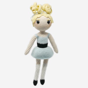 May include: A crocheted doll with blonde hair, a light blue dress with a black belt, and white socks and black shoes.