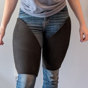 Könnte beinhalten: Eine Person trägt eine blaue Jeans mit schwarzen Stoffbahnen, die an den Oberschenkeln angenäht sind.