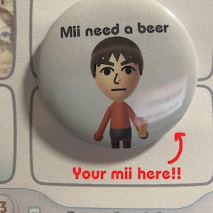 May include: A circular badge featuring a cartoon Mii character holding a beer, with the words "Mii need a beer." The text "Your mii here!!" is written in red below the badge. The background is white.