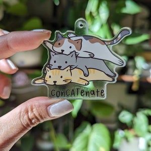 May include: A clear acrylic charm featuring three cartoon cats stacked on top of each other. The top cat is white, brown, and gray, the middle cat is gray, and the bottom cat is yellow with orange stripes. The word "ConCATenate" is printed at the bottom.