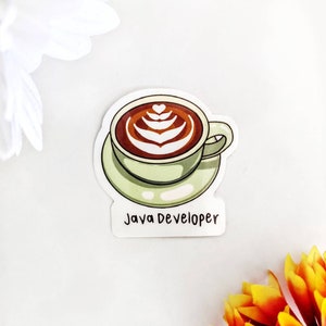 Może przedstawiać: Naklejka przedstawiająca filiżankę kawy z latte art, spoczywającą na spodku. Kawa jest brązowa z białymi wzorami. Filiżanka i spodek są jasnozielone. Pod filiżanką znajduje się napis "Java Developer".