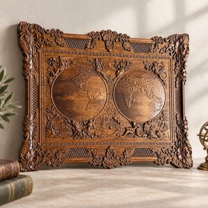 May include: A rectangular wooden wall plaque featuring a detailed relief carving of a double-hemisphere world map. The frame is decorated with ornate floral and scrollwork patterns, and the central map is surrounded by carved figures.