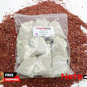 May include: A clear plastic bag filled with 10 small white fabric pouches. The pouches are labeled "Nateco" and "Teav". The bag is sitting on a pile of red wood chips.