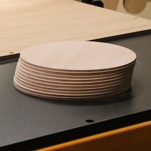 May include: A stack of round, unfinished wooden discs, likely for crafting or woodworking projects.