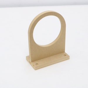 May include: A wooden wall mount with a circular cutout, designed to hold a round object. The mount has a rectangular base with two visible screw holes.