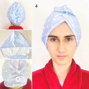 Pode incluir: Uma toalha de cabelo de microfibra azul claro com bolinhas brancas. A toalha tem um fecho de botão e está enrolada à volta da cabeça de uma pessoa.