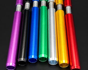 May include: A set of seven cylindrical metal tubes in purple, black, blue, green, silver, gold, and red. Each tube features a smooth, solid-colored body with a metallic finish and a silver-toned, ribbed spring-like section at the top.