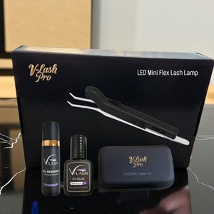 May include: A black box set with the text "V-Lash Pro" and "LED Mini Flex Lash Lamp". The set includes a gel remover, UV glue, tweezers, and a small black case with the text "V-Lash Pro Essentials Carry Kit".
