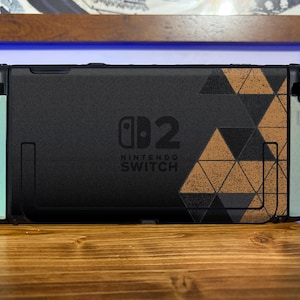 May include: A black Nintendo Switch console featuring a custom skin with a geometric triangle pattern in black and tan on the right side. The left and right edges are light mint green, and the center displays the Nintendo Switch 2 logo in black.
