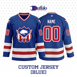 May include: Blue hockey jersey with white and red accents. Features a team logo with a buffalo and crossed hockey sticks. The jersey has the text "NAME" and the number "00" on the back. The text "CUSTOM JERSEY (BLUE)" is at the bottom.