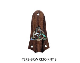 May include: A dark brown wooden guitar truss rod cover featuring a central inlaid triquetra knot design made of iridescent abalone shell and white mother of pearl. The piece has three pre-drilled mounting holes and the text TLR3-BRW CLTC-KNT 3.