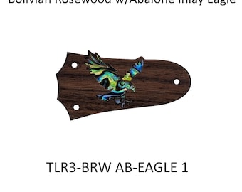 May include: A dark brown Bolivian rosewood guitar truss rod cover featuring an iridescent abalone inlay of an eagle in flight. The piece has three pre-drilled mounting holes and is labeled with the text Bolivian Rosewood w/Abalone Inlay Eagle and TLR3-BRW AB-EAGLE 1.