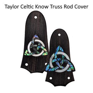 May include: Two dark wood guitar truss rod covers, each featuring a central Celtic knot inlay made of iridescent abalone shell and white mother-of-pearl. The text Taylor Celtic Know Truss Rod Cover is displayed above the two guitar components.