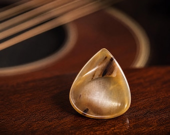 May include: A teardrop-shaped guitar pick with a translucent, polished finish featuring marbled beige, tan, and dark brown streaks. The pick has a smooth, glossy surface and is marked with the text TP-22 in the bottom right corner of the image.