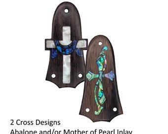 May include: Two dark brown wooden guitar truss rod covers with pre-drilled holes. One features a white mother of pearl cross inlay with a blue abalone crescent. The other displays an ornate cross design crafted from iridescent green abalone shell.