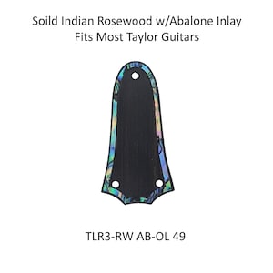 Può includere: Un battipenna per chitarra in palissandro indiano massiccio con intarsio di abalone. Il battipenna è nero con bordi iridescenti e presenta tre fori. Il testo "Soild Indian Rosewood w/Abalone Inlay Fits Most Taylor Guitars" è in alto e "TLR3-RW AB-OL 49" in basso.