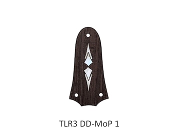 May include: A dark brown wooden guitar truss rod cover with a bell shape, featuring two white mother-of-pearl diamond-shaped inlays and three pre-drilled mounting holes. The text TLR3 DD-MoP 1 is printed in black below the object.