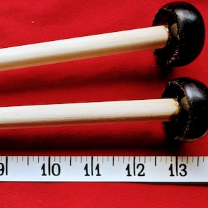 May include: Two wooden mallets with black rubber heads. The mallets are approximately 11 inches long. A white measuring tape is visible in the background.