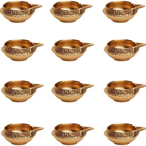 May include: Set of twelve gold-colored brass diya oil lamps with intricate designs. Each diya has a small, round bowl for oil and a wick.