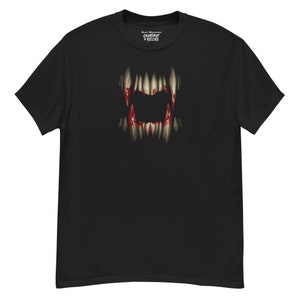 May include: Black t-shirt featuring a graphic of a menacing set of teeth with blood-like red accents. The shirt has the text "Creatures + Killers" at the top. The t-shirt is made of a soft, comfortable material.