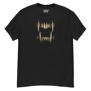 May include: Black t-shirt featuring a detailed illustration of a monster's teeth. The teeth are a light beige color, contrasting against the dark background. The shirt also has the text "Creatures + Killers" printed on the top.