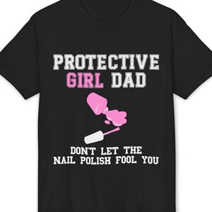 以下が含まれることがあります： 黒いTシャツ。白とピンクで「PROTECTIVE GIRL DAD」の文字。その下にピンクのマニキュアボトルからこぼれるマニキュアと、白で「DON'T LET THE NAIL POLISH FOOL YOU」の文字。