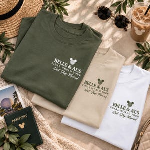 May include: Three crew neck t-shirts in olive green, beige, and white. Each shirt features a small chest print with a mouse ear icon and the text: BELLE & AL'S FINAL WORLD TOUR Next Stop: Married. The shirts are arranged in a layered stack.