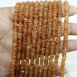 May include: A strand of orange gemstone beads, each bead is a small, faceted, rectangular shape.